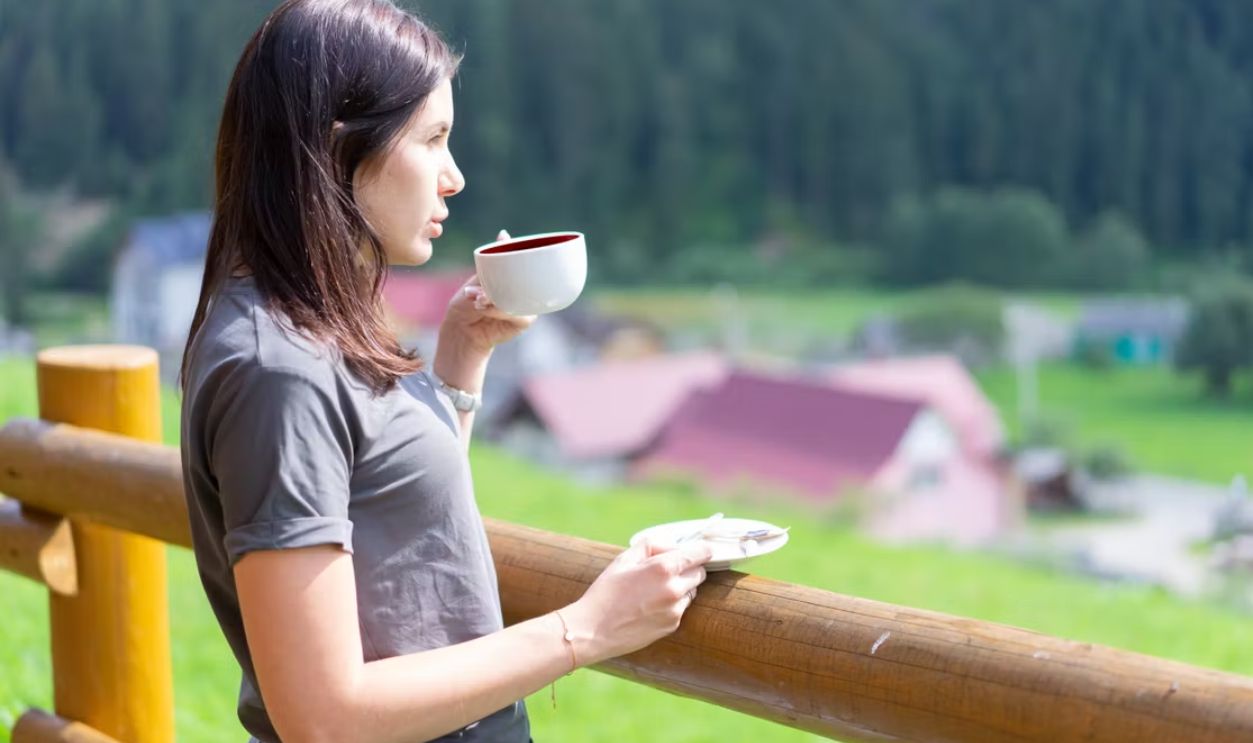Caucasian woman savoring a morning coffee outdoors in scenic Bukovel, Ukraine