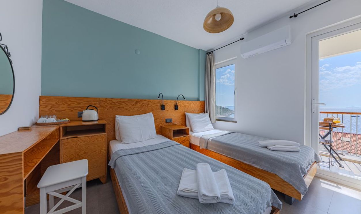 Bright hotel room with twin beds and ocean view balcony. Perfect for travelers