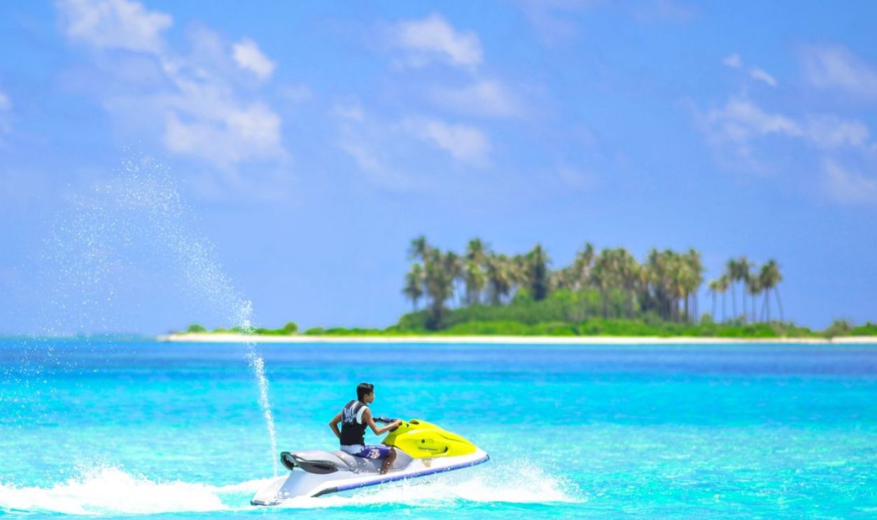 Vibrant jet ski adventure near a picturesque island in the tropical Maldives with clear blue waters and palm trees