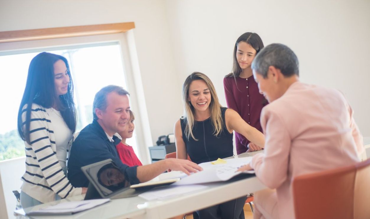 A happy family gathering around a desk during a home meeting, discussing documents.