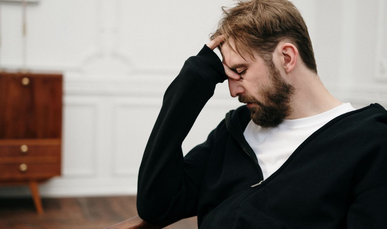 A man sits pensively with his hand on his face