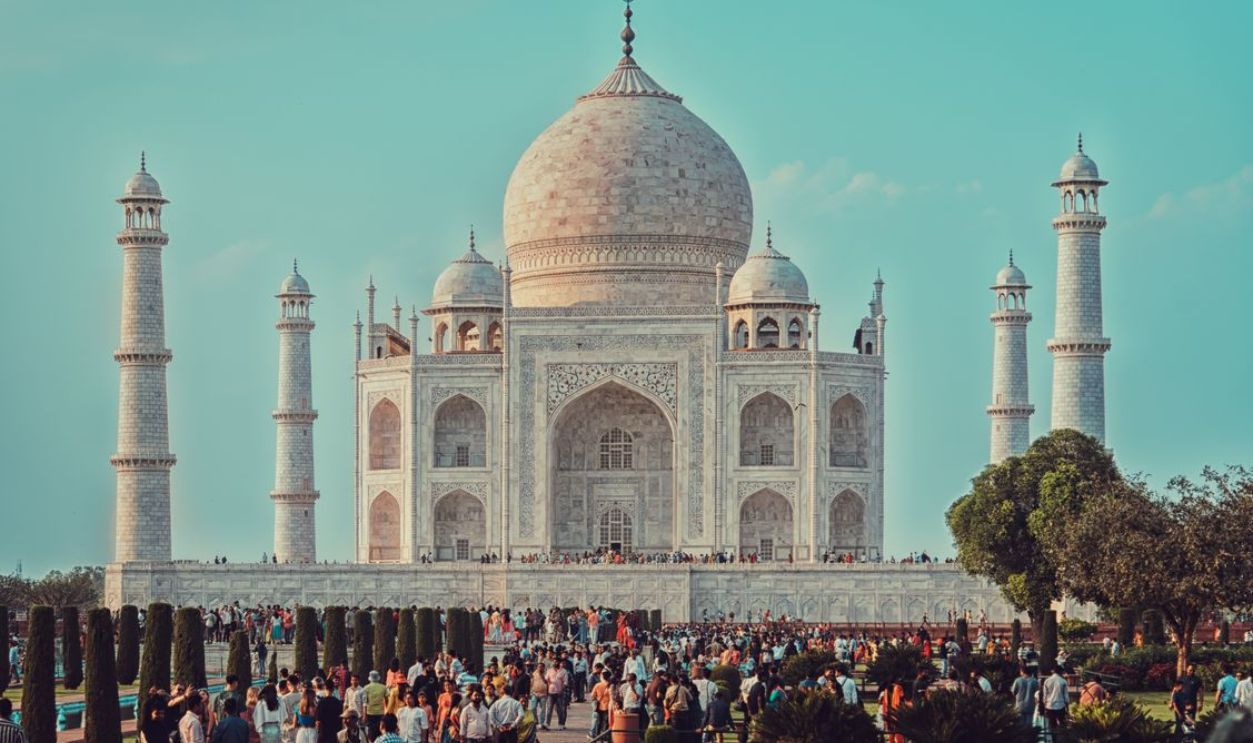Iconic Taj Mahal in Agra, India, with a crowd enjoying the view on a sunny day.