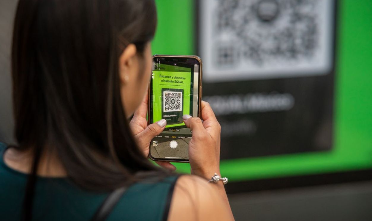 A woman uses her smartphone to scan a QR code in Mexico City, capturing modern technology in action.