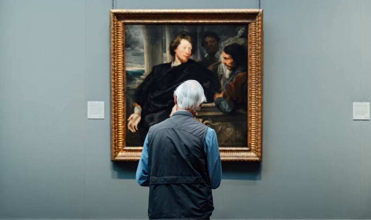 Senior admiring a classic painting in an English art gallery. Engrossed in art appreciation.