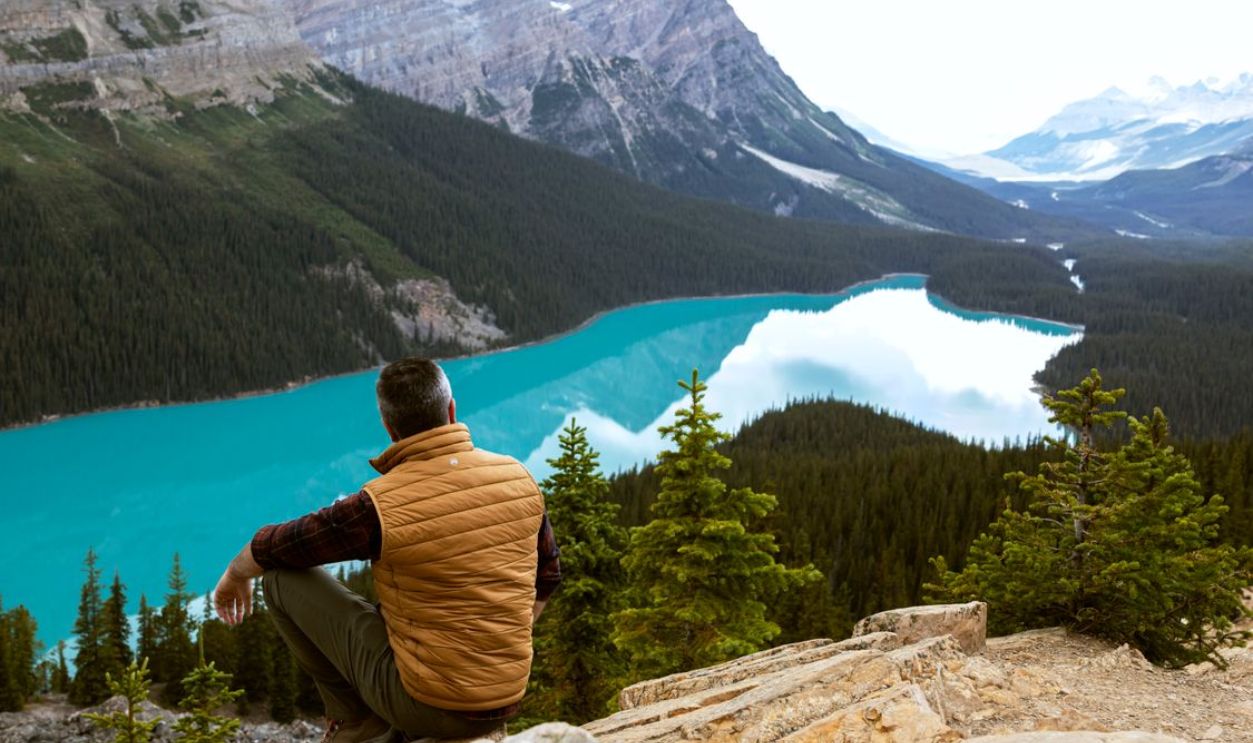 A man sits overlooking the breathtaking view of Peyto Lake in Banff National Park, Canada.
