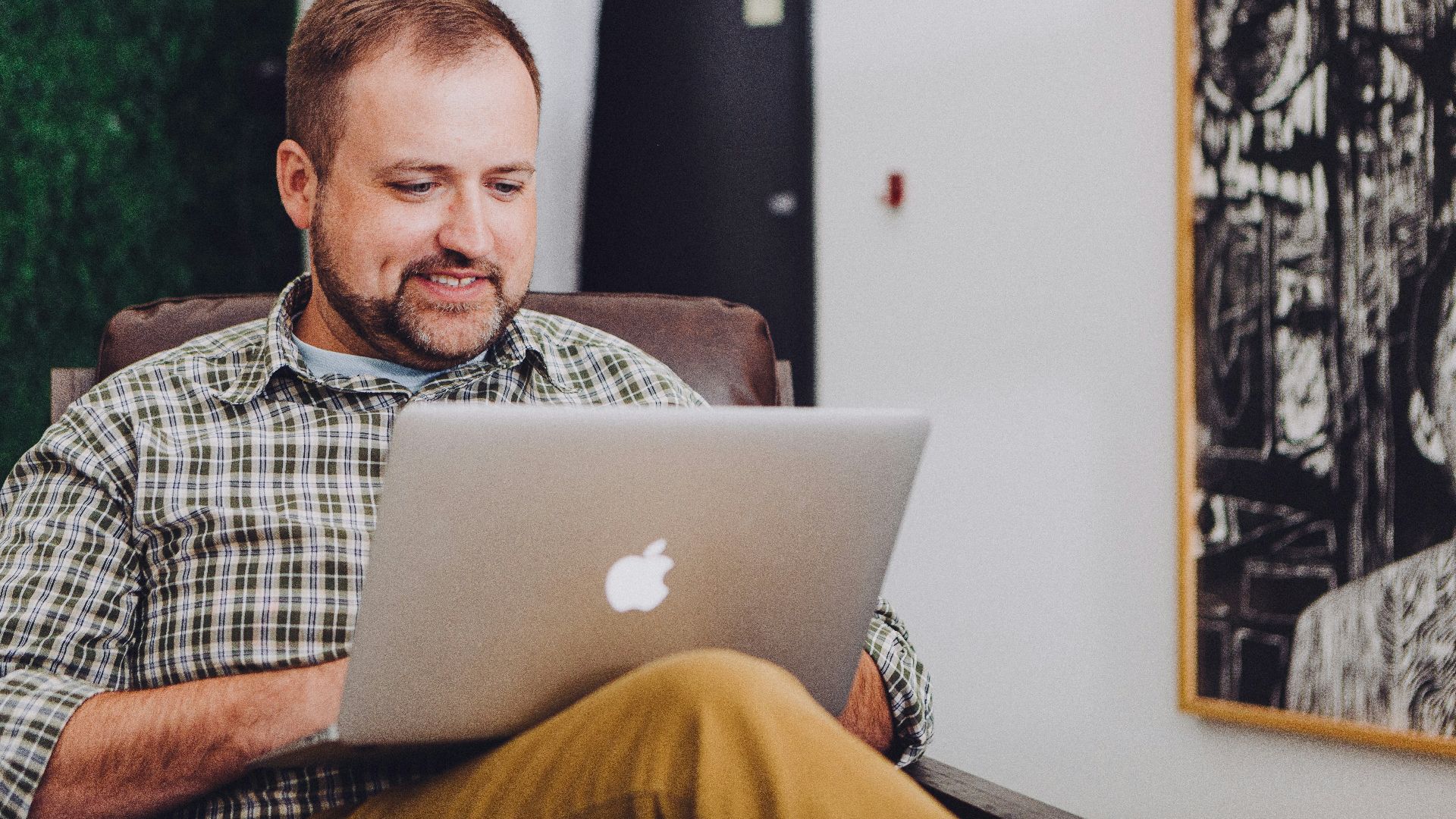 man smiling and using MacBook