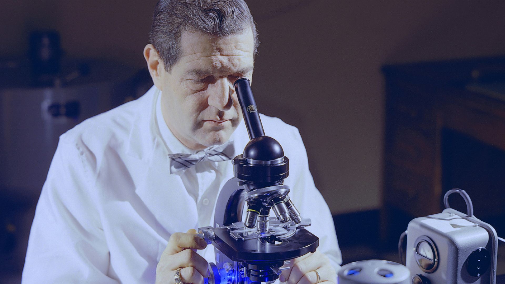 a man looking through a microscope at something