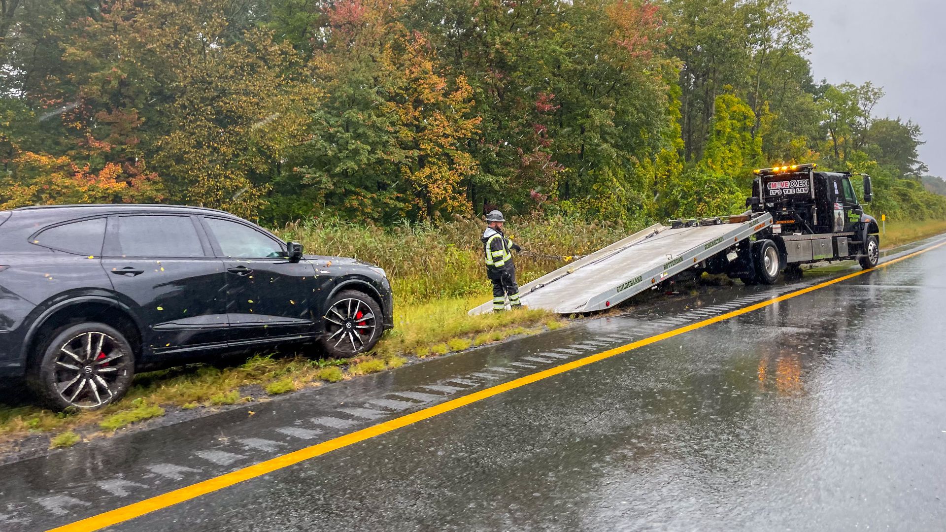 Roadside assistance along I-90 in Albany, New York, during a rainstorm.