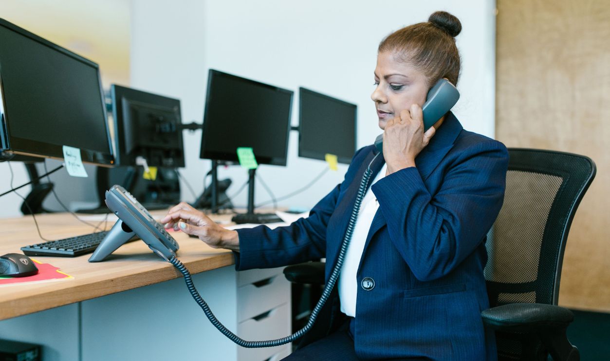 Businesswoman multitasking in office, using phone and computer
