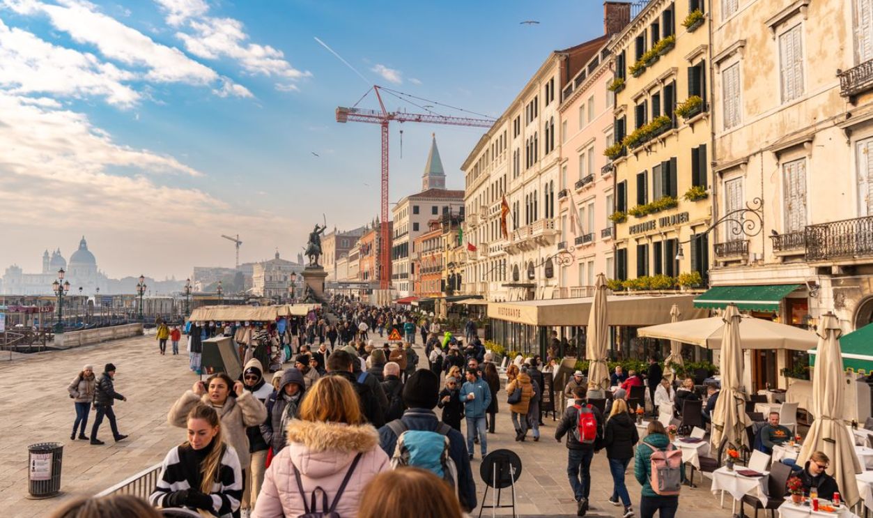 Crowded street in Venice, Italy showcasing vibrant urban life along colorful buildings.