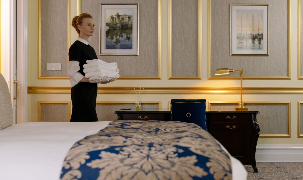 A housekeeper holding towels in a luxurious hotel room