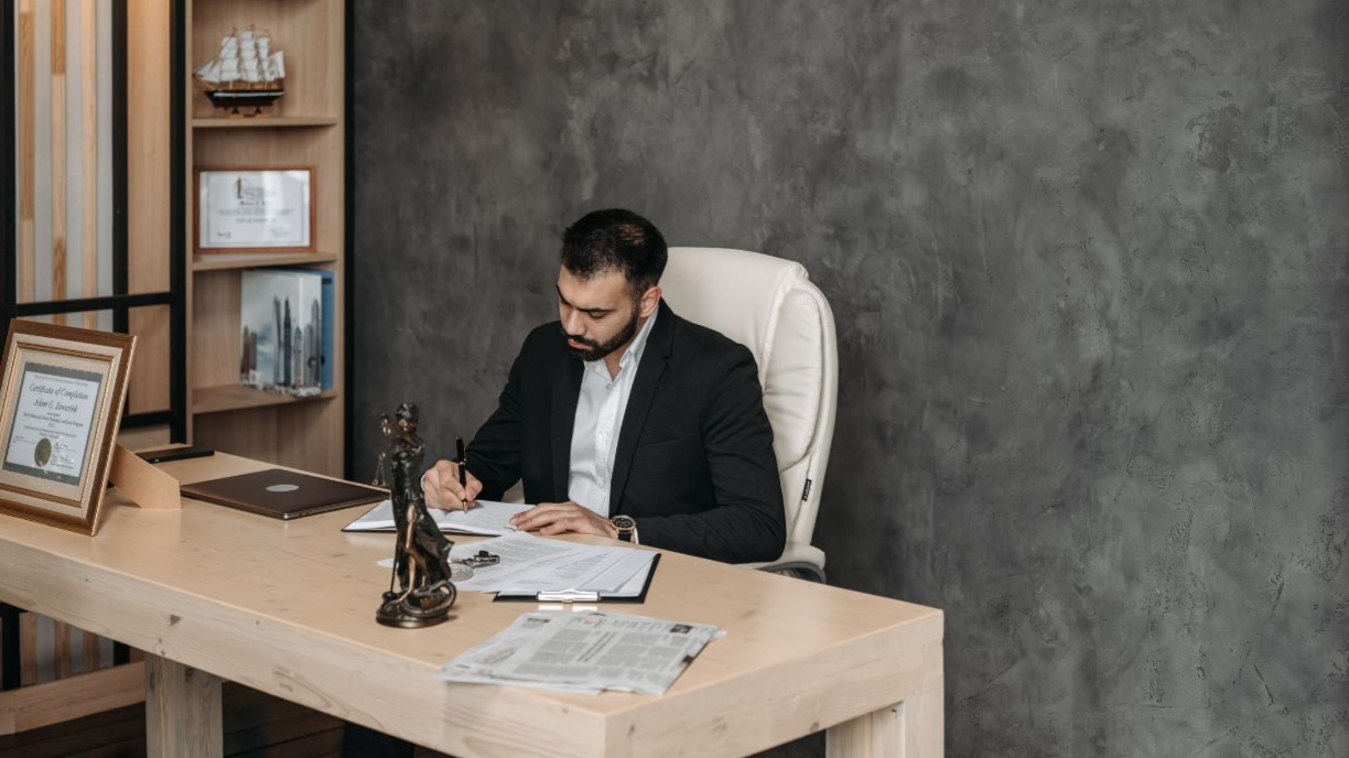 Businessman in a suit writing at a desk in a modern office