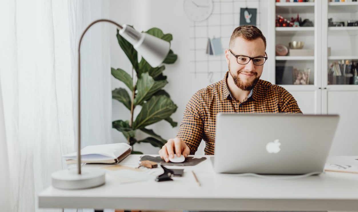 Adult male working remotely in a stylish home office with a laptop, displaying a modern workspace.