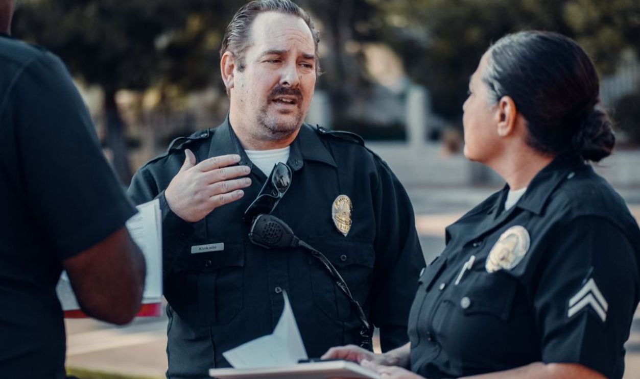 Three police officers engage in conversation outdoors, showcasing teamwork