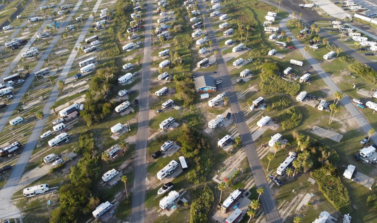 Aerial shot of a lush campsite filled with RVs and trailers during the day
