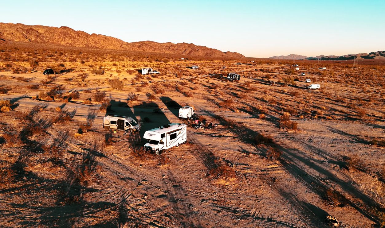Aerial shot of RVs camped in a desert landscape at sunset, highlighting adventure travel