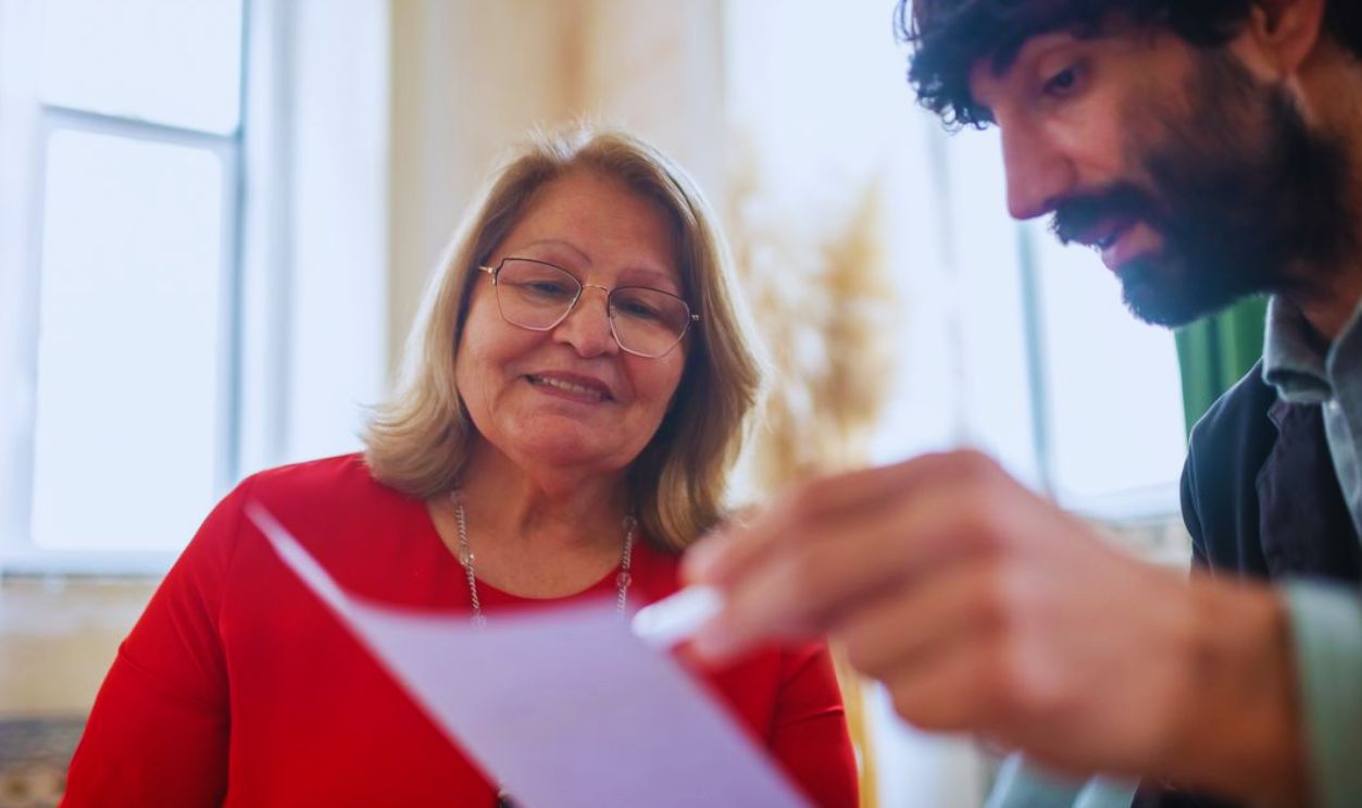 Elderly woman and bearded man in a consultation meeting reviewing documents indoors