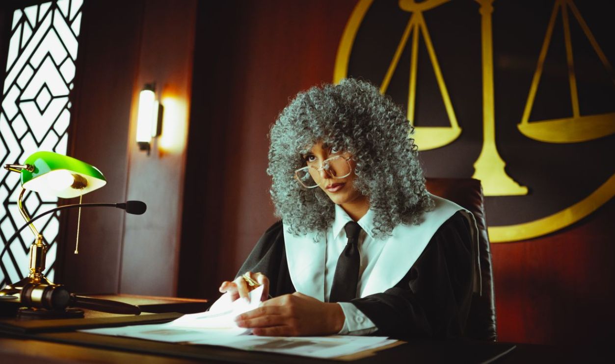 A judge in a courtroom examining documents under a classic green lamp