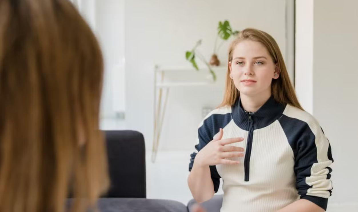 Women having a conversation at home, sitting on a sofa in a light living room