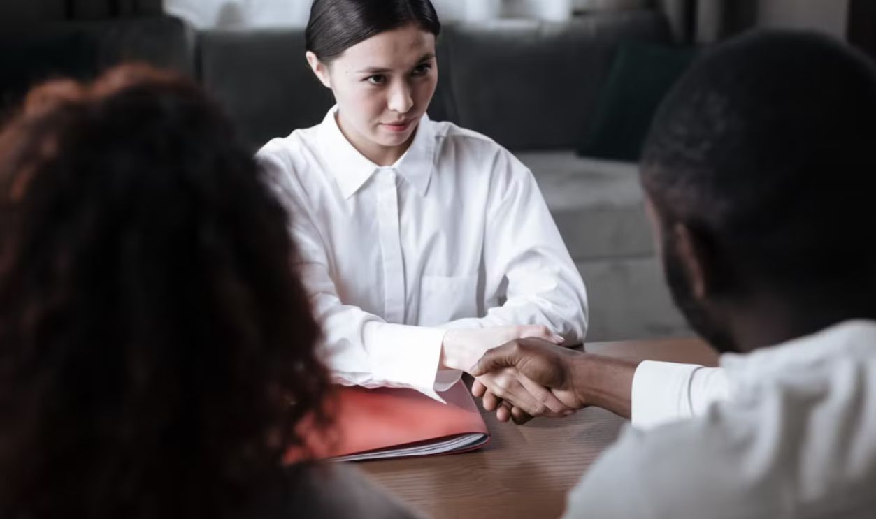 A diverse meeting between a social worker and couple indoors, emphasizing trust and collaboration