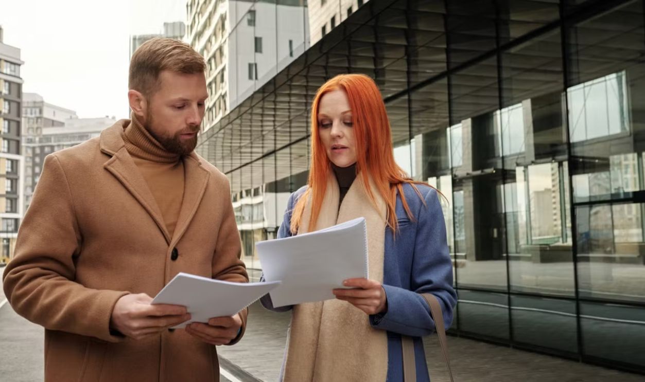 Two business professionals in urban setting reviewing documents together