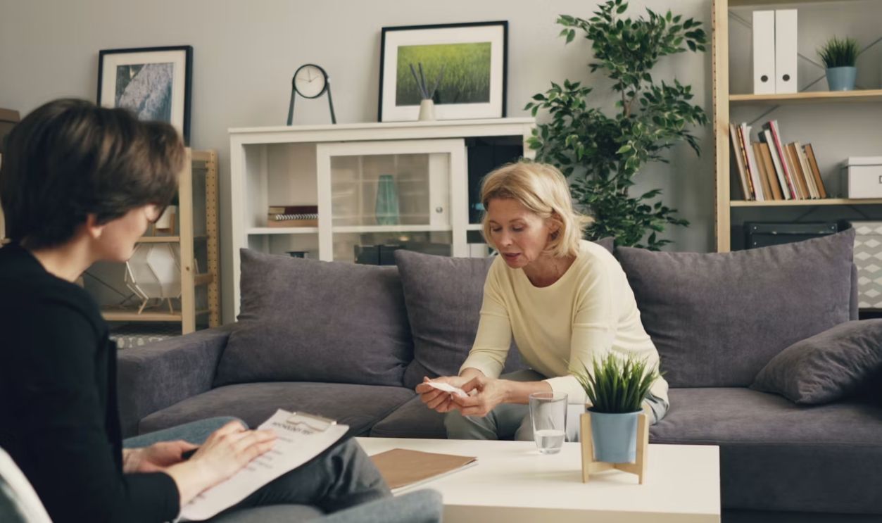 a woman sitting on a couch talking to another woman