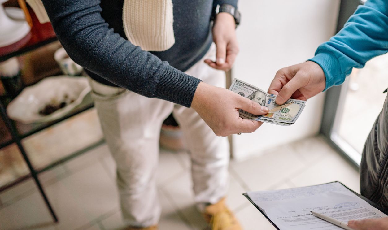 Close-up of hands exchanging cash during a transaction indoors, highlighting payment details