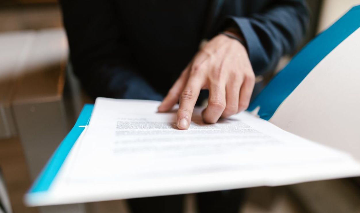 Close-up of a hand pointing at text on a business document in an office environment