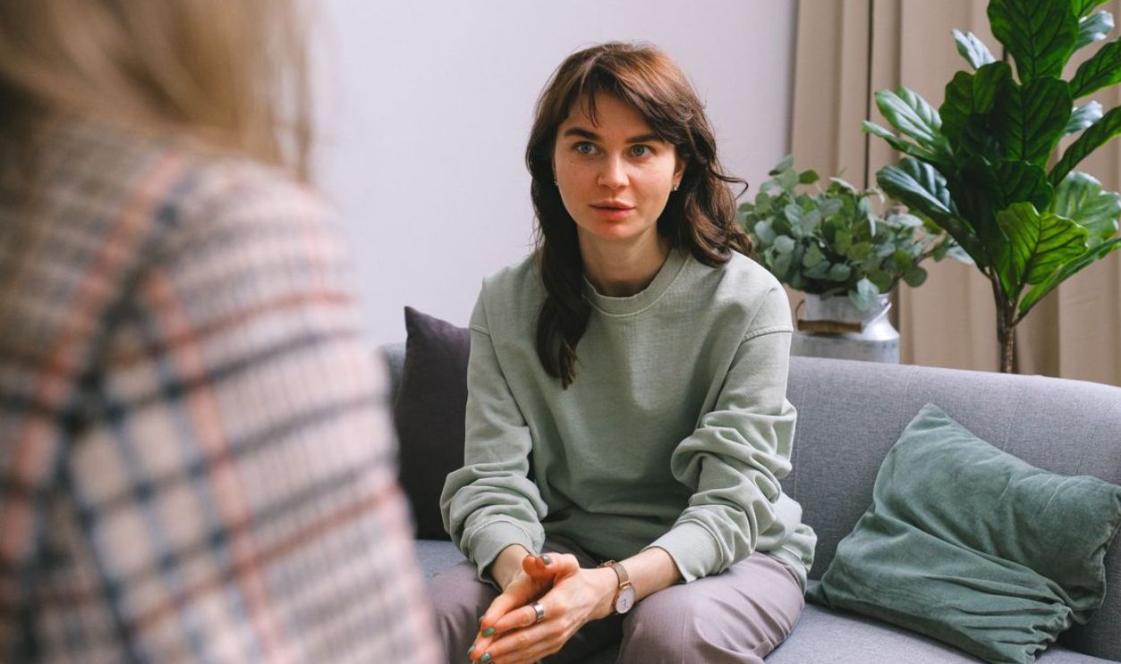 A focused woman during a therapy session, seated on a sofa indoors