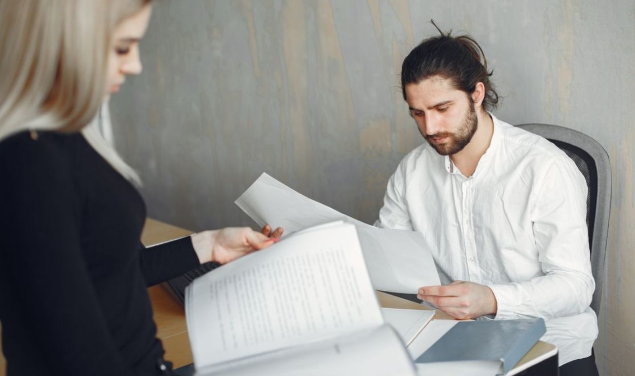 Two professionals reviewing important documents in a modern office setting