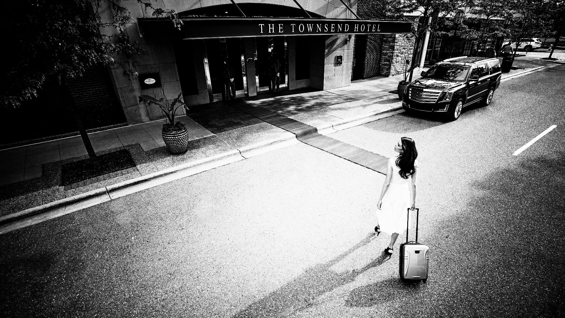 greyscale of women pulling luggage bag