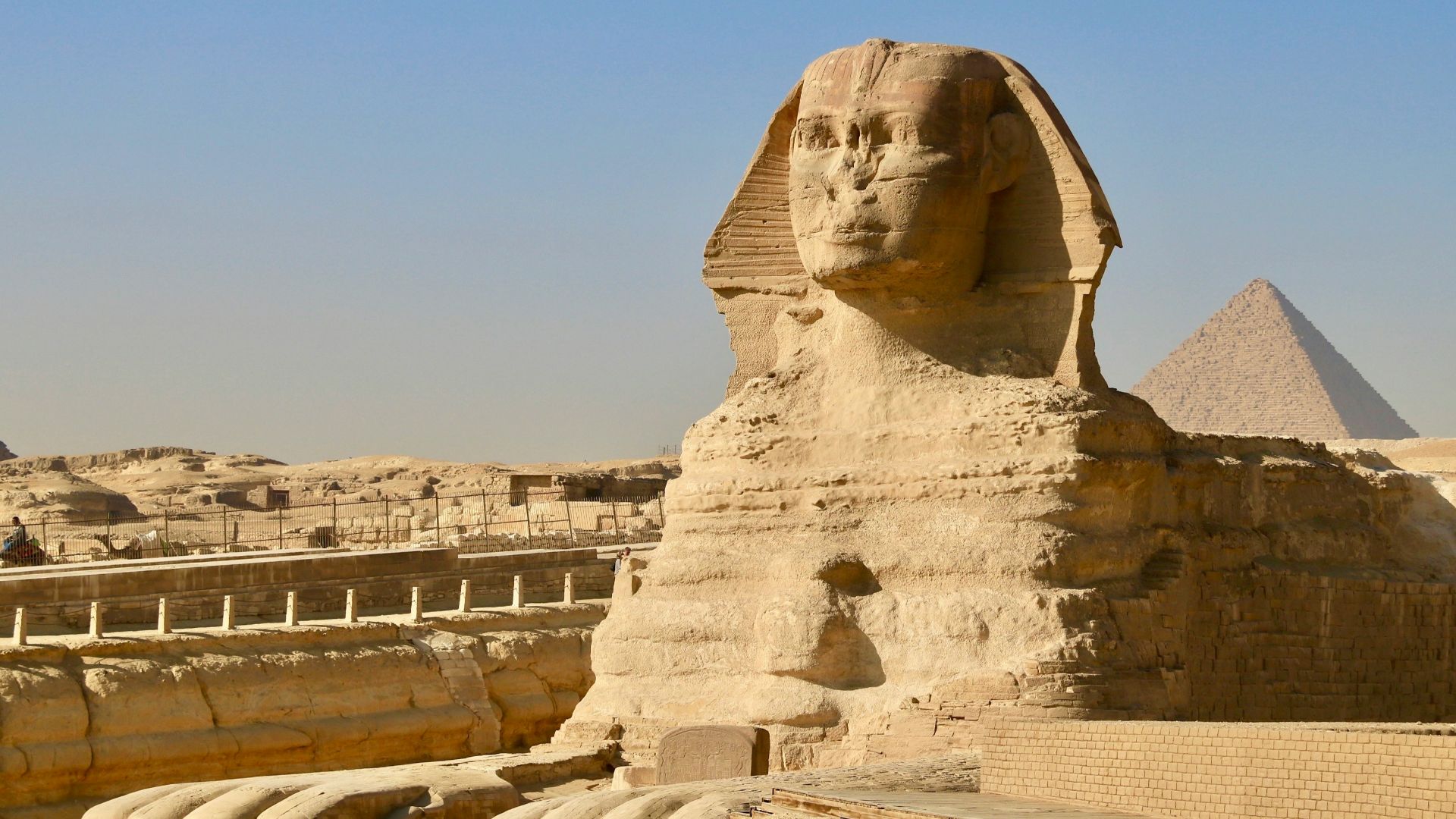 a large stone sculpture with Great Sphinx of Giza in the background