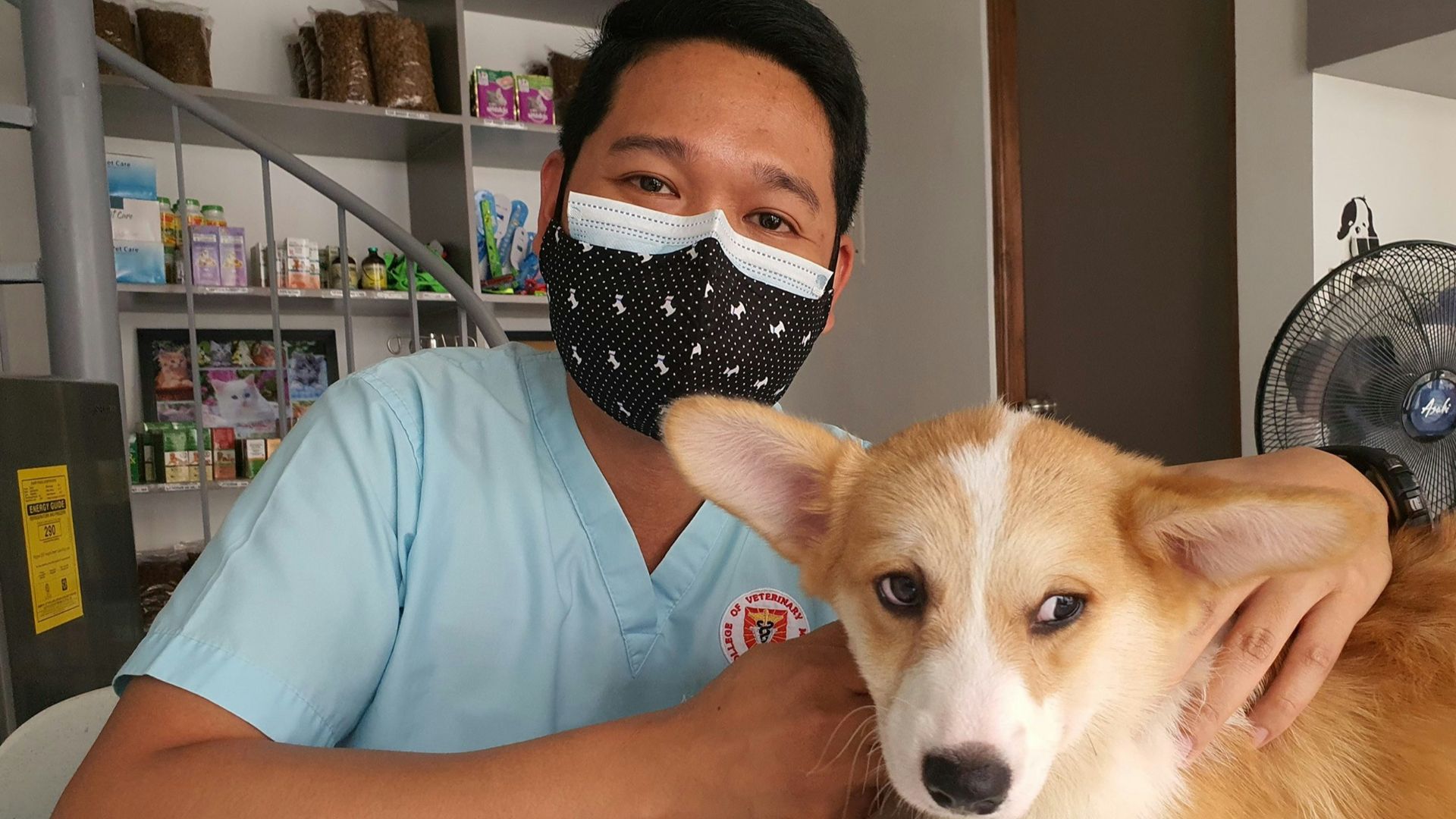 a man wearing a face mask sitting next to a dog