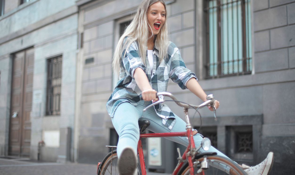 Smiling woman riding a vintage bicycle in a lively city street.