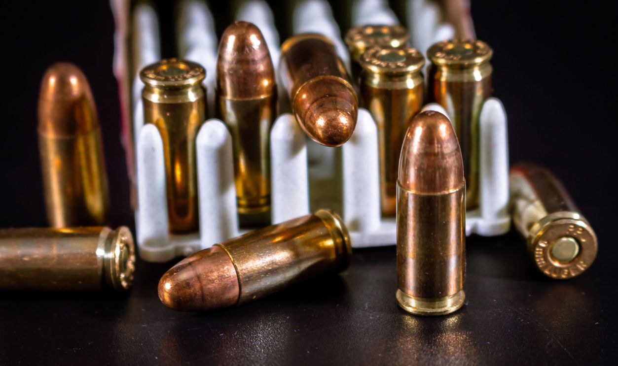 Detailed close-up of bullets arranged on a black surface, showcasing ammunition and brass casings.