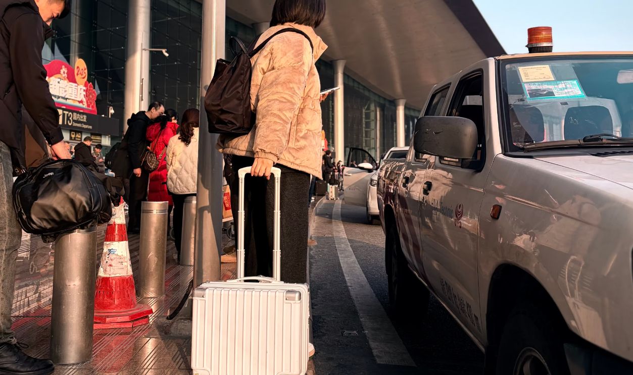 Adult at airport curbside with suitcase, ready to travel. Modern terminal scene