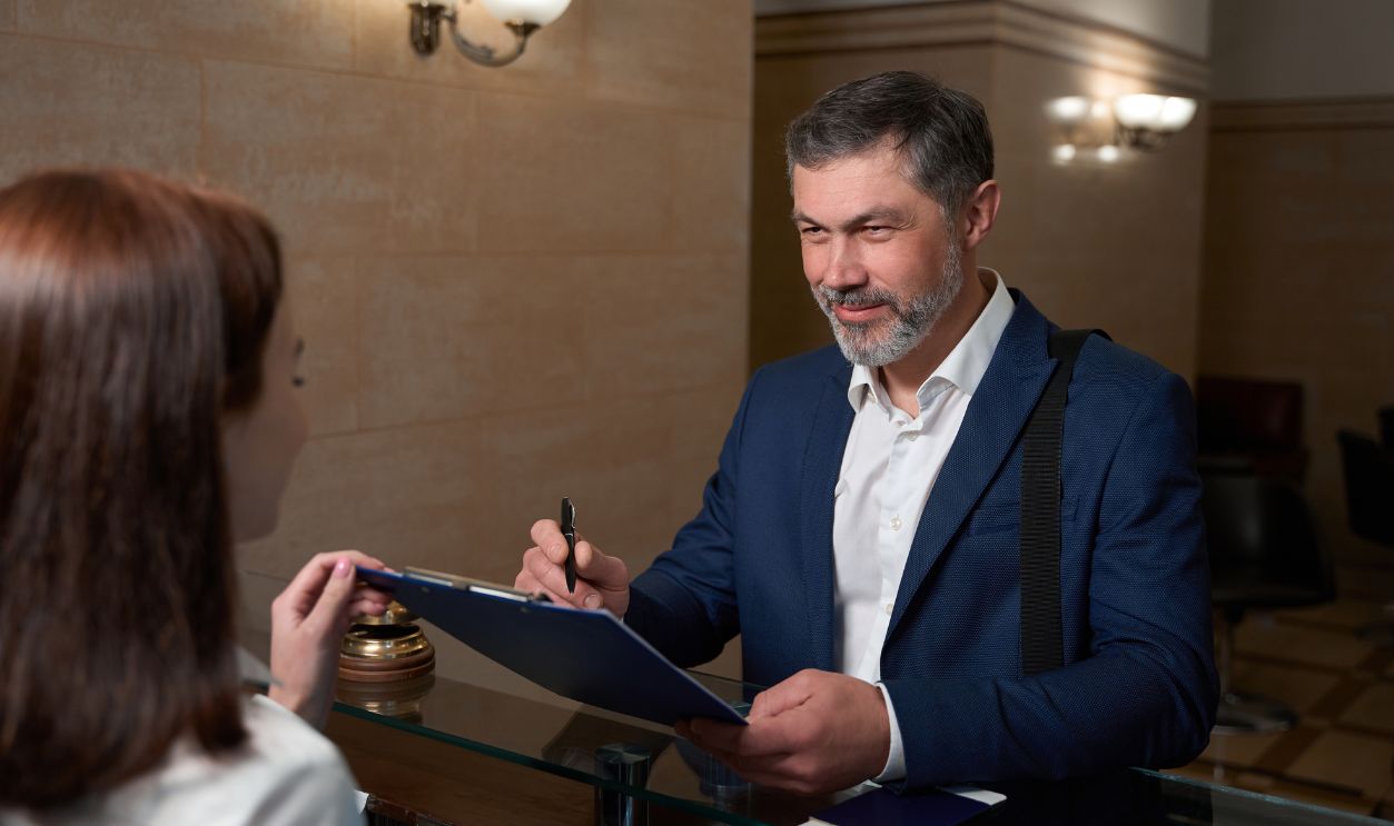 Shutterstock-2291585257, Man came to hotel and signs document