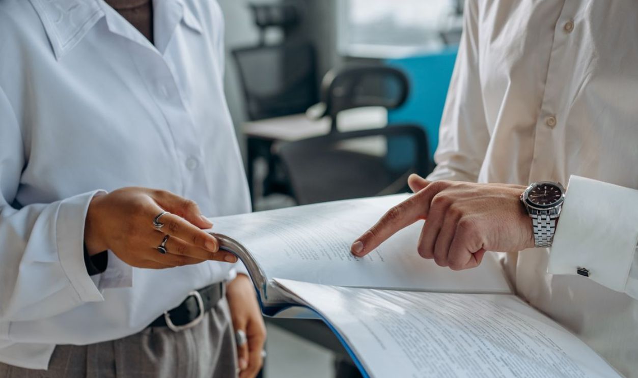 Two business professionals discussing and reviewing documents in a modern office setting