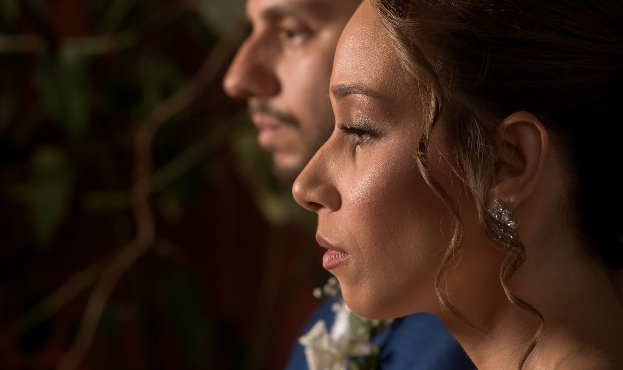A close profile view of a sophisticated couple dressed for a wedding, capturing a tender moment