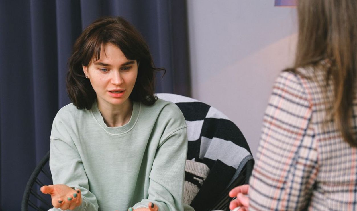 Two women having a thoughtful discussion in a therapy session within a cozy room setting