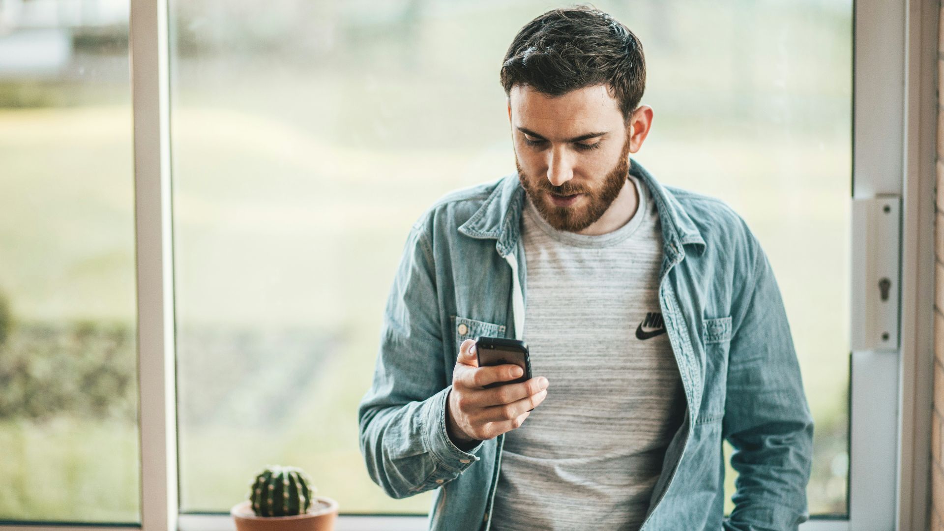 man holding a smartphone near the window