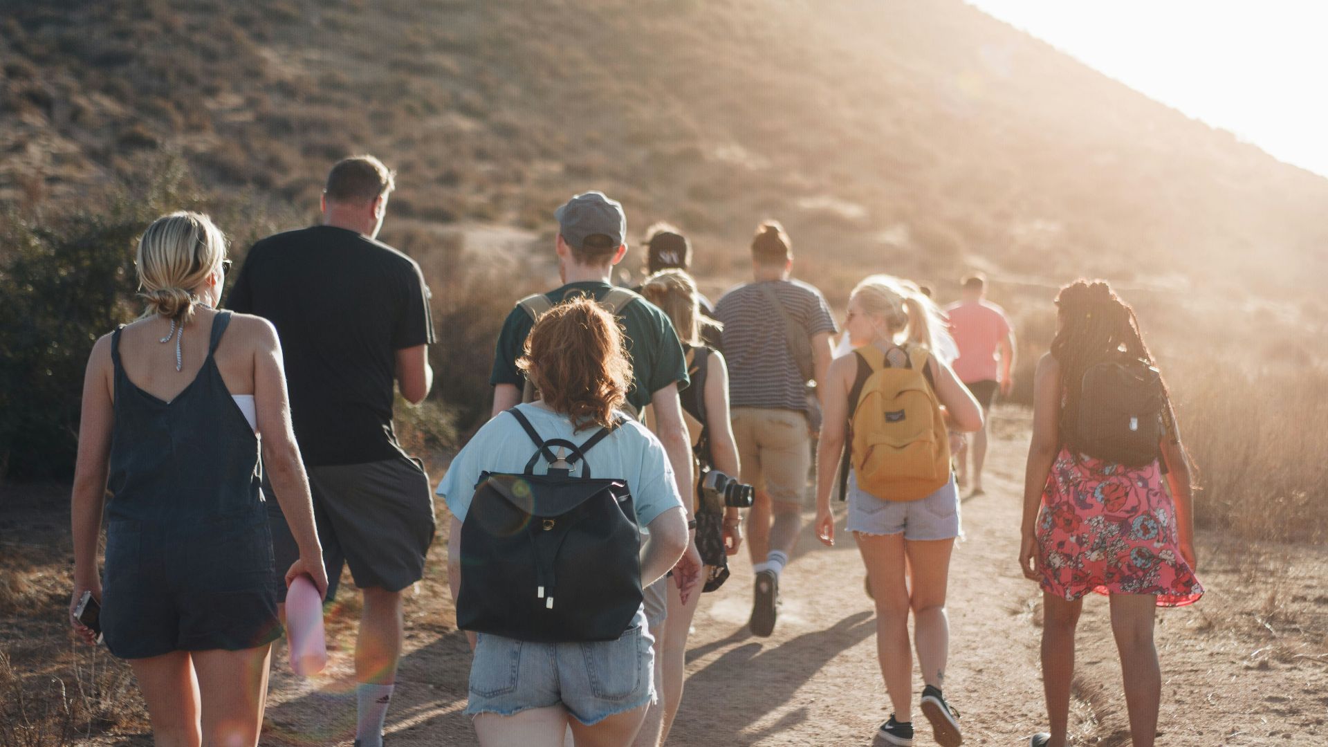 people walking on dirt road near mountain during daytime