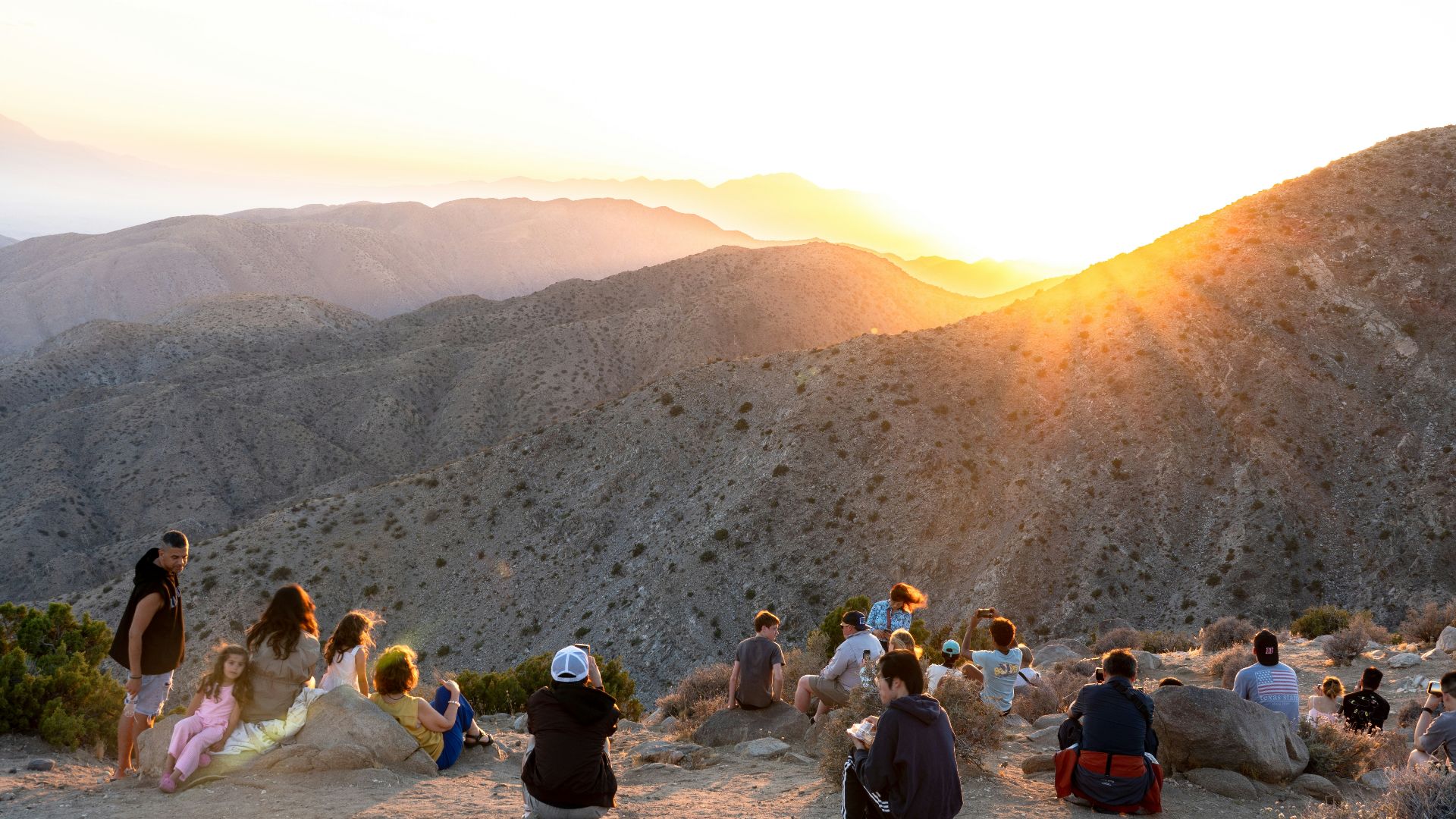 Group of people watching a beautiful sunset over desert mountains.