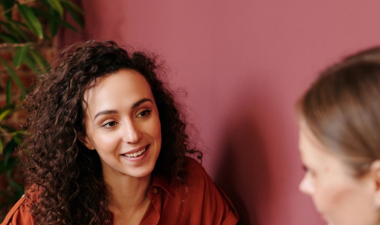 Two women engage in a collaborative discussion at a coffee shop table, sharing ideas and smiles