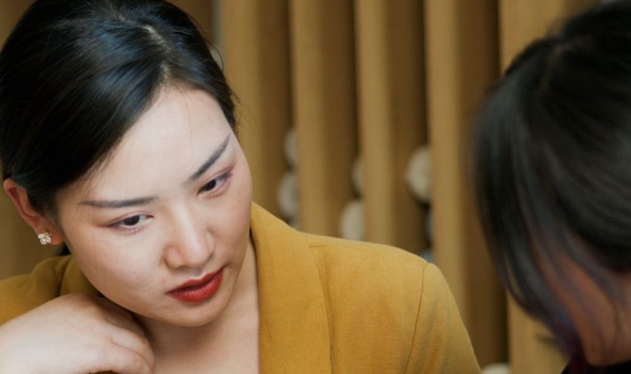 Two women in professional attire engaged in a thoughtful office discussion
