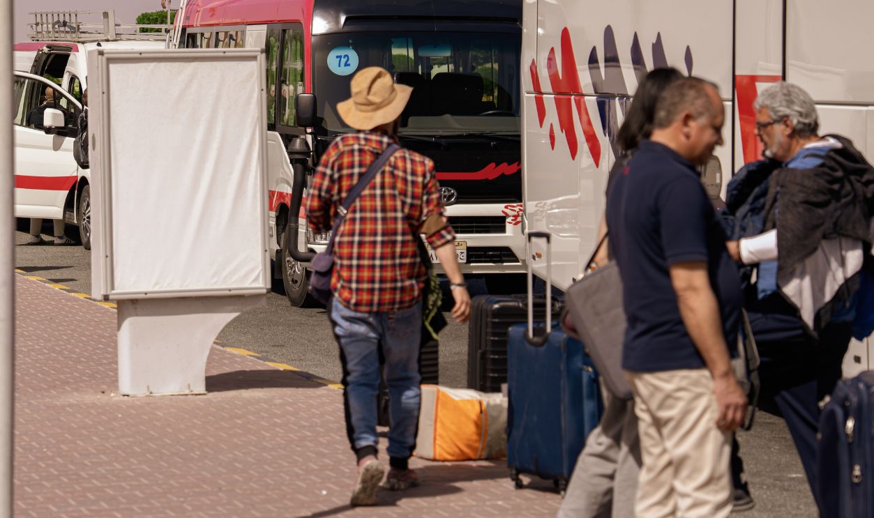 Marsa alam, egypt 21 april 2026: tourists with luggage boarding shuttle buses at a sunny marsa alam terminal, preparing for airport transfer to resorts