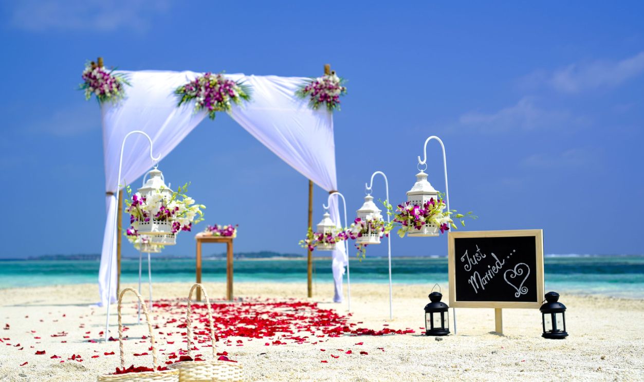 Stunning beach wedding arrangement with floral decor and lanterns on a sunny day
