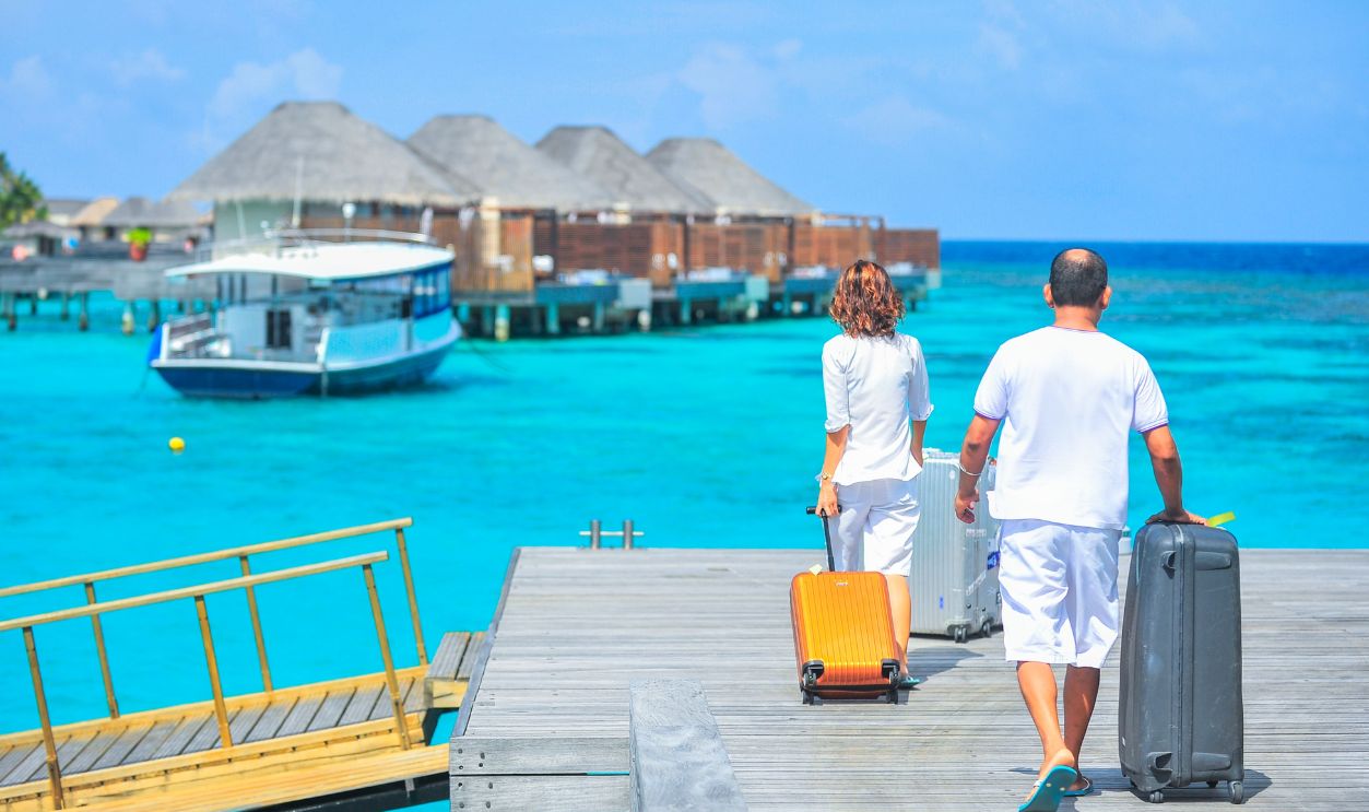 A couple arriving at a luxurious Maldives resort dock with luggage, capturing a tropical vacation vibe
