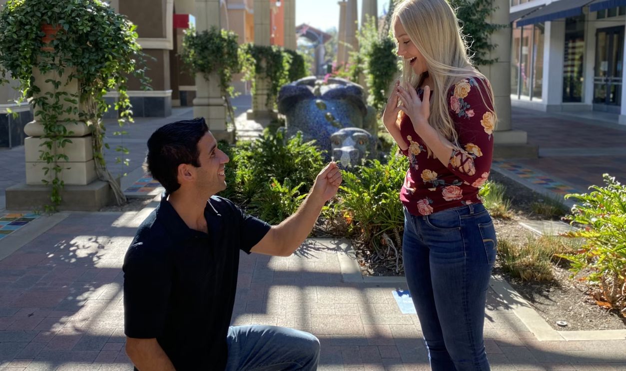 man in black crew neck t-shirt and blue denim jeans holding woman in red and