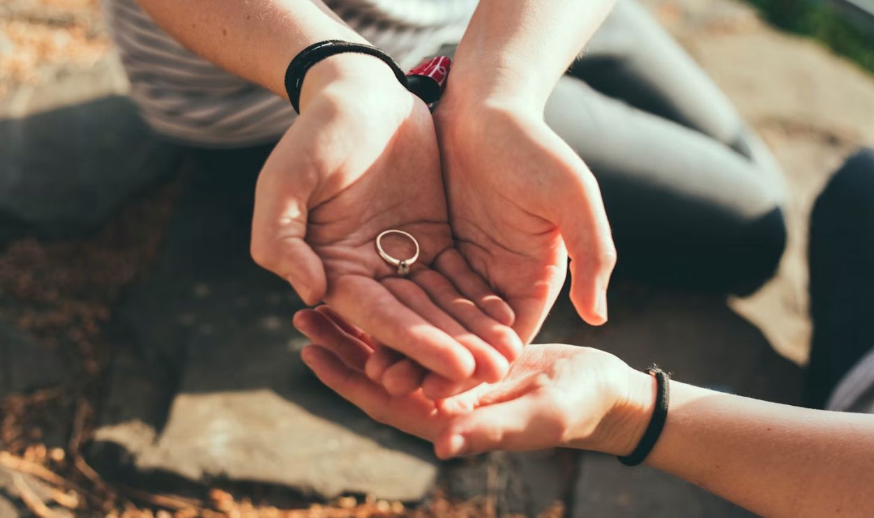 person giving ring to another hand during daytime